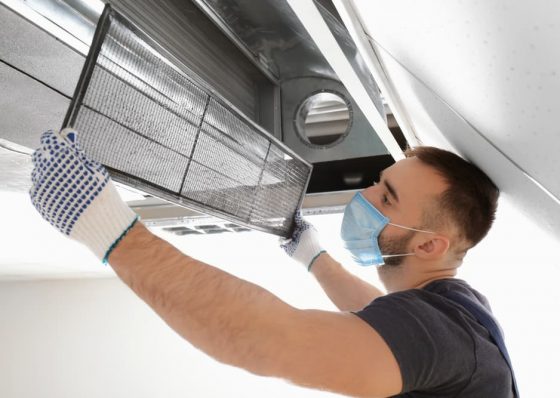 Male technician cleaning industrial air conditioner — Air Conditioning Solutions In Tweed Heads, NSW