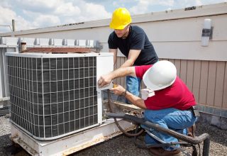 Two air conditioner specialist fixing air conditioner — Air Conditioning Solutions In Tweed Heads, NSW